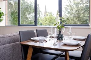 mesa de comedor con sillas y mesa de madera con gafas en Stylish and Bright 2 Bedroom Apartment Manchester, en Mánchester
