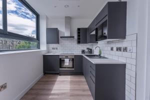 eine Küche mit schwarzen und weißen Geräten und einem Fenster in der Unterkunft Charming Studio Apartment in Central Sheffield in Sheffield