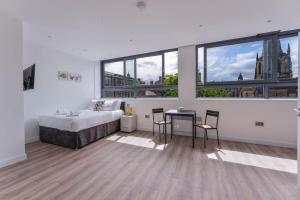 Modern and Bright Studio in Central Sheffield في شيفيلد: غرفة نوم بيضاء بسرير وطاولة وكراسي