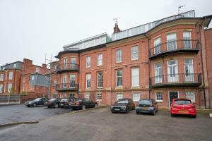 een groot bakstenen gebouw met auto's geparkeerd op een parkeerplaats bij Beautiful 2 Bed Apartment in Preston in Preston