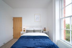 een witte slaapkamer met een bed en 2 ramen bij Beautiful 2 Bed Apartment in Preston in Preston