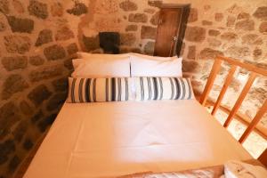 a twin bed in a room with a stone wall at Petromilos1920 in Zefiría