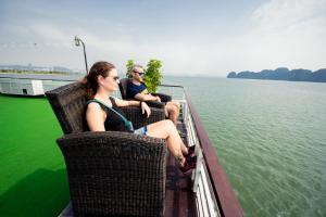 two people sitting in chairs on a boat on the water at Dragon Crown Legend Cruise in Ha Long