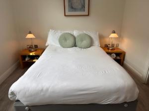 a white bed with two green pillows on it at Gallery Apartments in London