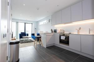 eine Küche mit weißen Schränken und ein Wohnzimmer in der Unterkunft Stunning 2 Bedroom Apartment Manchester in Manchester