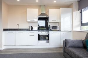 een keuken met witte kasten en een bank bij Contemporary 2 Bed Apartment Salford in Manchester