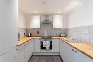 a kitchen with white cabinets and wooden counter tops at Charming 1 Bedroom Apartment in Leeds in Leeds