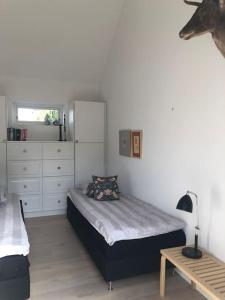 a bedroom with a bed and a dresser and a table at Cozy, quiet guest house perfect for business or pleasure in Hillerød