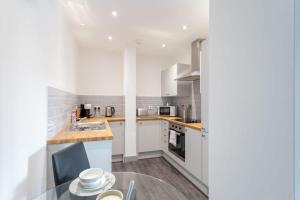 a kitchen with white cabinets and a glass table at Modern 1 Bedroom Apartment Leeds in Leeds