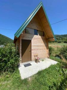um pequeno edifício de madeira com uma porta e um banco em Bungalov Perovic em Andrijevica
