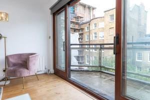 Habitación con ventana grande y silla en Spacious 1 Bed Mayfair Apartment with Balcony, en Londres