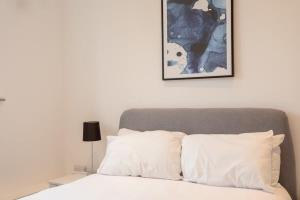 Amazing 1 Bedroom Apartment Leeds في ليدز: سرير ومخدات بيضاء وصورة على الحائط