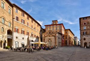 a group of people sitting at tables in a city street at The Bank Hotel - Locanda della Posta Dependance in Perugia