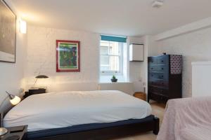 a bedroom with a white bed and a black dresser at Charming 1 Bedroom Apartment in old School House in London