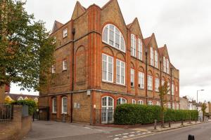a large brick building with white windows on a street at Charming 1 Bedroom Apartment in old School House in London