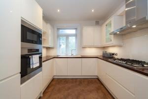 a kitchen with white cabinets and a stove top oven at Spacious 2 Bedroom Maisonette in Stratford in London