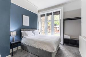 a blue bedroom with a large bed and a window at Beautiful Apartment in a stone built Victorian residence in Leeds