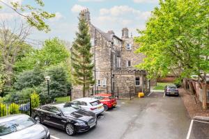 an old stone house with cars parked in front of it at Beautiful Apartment in a stone built Victorian residence in Leeds