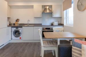 a kitchen with a table and a sink and a washing machine at Contemporary 1 Bedroom Apartment in Ashford in Ashford