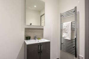 a white bathroom with a sink and a mirror at Lovely Compact 1 Bed Apartment in Leeds in Leeds