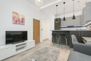 沃金的住宿－Modern 1 Bedroom Apartment in Central Woking，厨房以及带电视和柜台的起居室。