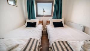 two twin beds in a room with a window at Lovely 2 Bedroom Coastal Cottage near Bude in Bude