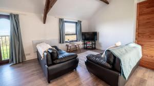a living room with two leather couches and a television at Lovely 2 Bedroom Holiday Cottage nr Bude in Bude