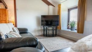 a living room with a couch and a flat screen tv at Lovely 3 Bedroom Holiday Cottage nr Bude in Bude