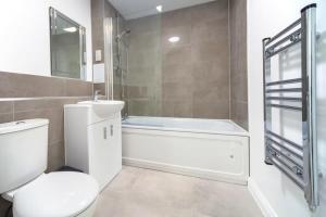 a bathroom with a toilet and a tub and a sink at Contemporary 2 Bedroom Apartment in Ashford in Ashford