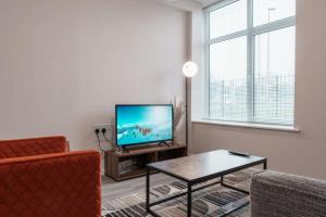 uma sala de estar com uma televisão, um sofá e uma mesa em Modern 2 Bed Apartment in Manchester - Sleeps 4 em Manchester