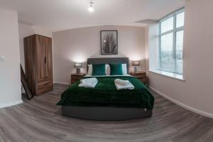 um quarto com uma cama grande com cobertores e almofadas verdes em Modern 2 Bed Apartment in Manchester - Sleeps 4 em Manchester