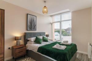 Schlafzimmer mit einem Bett mit grüner Bettwäsche und einem Fenster in der Unterkunft Lovely 1 Bedroom Manchester Apartment in Manchester