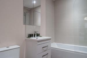 uma casa de banho branca com um lavatório e uma banheira em A Lovely Modern 1 Bed Apartment in Manchester em Manchester