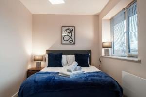- une chambre avec un lit doté de draps bleus et une fenêtre dans l'établissement A Lovely Modern 1 Bed Apartment in Manchester, à Manchester