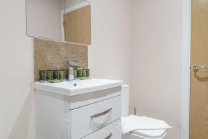 a white bathroom with a sink and a mirror at Fantastic 1 Bed Apartment Manchester - Sleeps 2 in Manchester