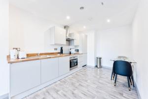 a kitchen with white cabinets and a black chair at Contemporary 1 Bed Apartment in Central Wolverhampton in Wolverhampton +16 photos