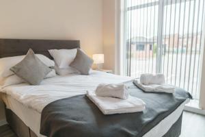 een wit bed met handdoeken en een raam bij Modern 1 Bedroom Apartment Manchester - Sleeps 2 in Manchester