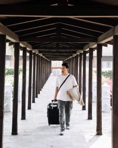 un homme marchant dans un couloir avec une valise dans l'établissement Hokke Lumbini, à Rummindei