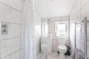 a white bathroom with a toilet and a window at Modern 2 Bedroom Apartment in Central Bradford in Bradford