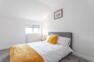 a bedroom with a white bed with a yellow pillow at 2 Bed Apartment Close to Bradford City Centre in Bradford