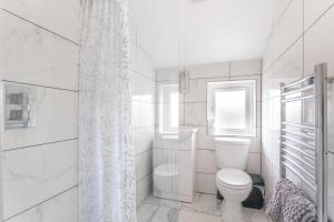a white bathroom with a toilet and a window at 2 Bed Apartment Close to Bradford City Centre in Bradford