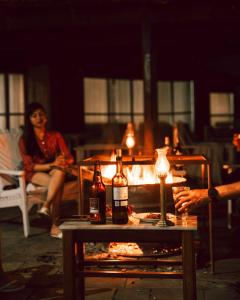 - une table avec des bouteilles d'alcool et une femme assise sur un patio dans l'établissement Hokke Lumbini, à Rummindei