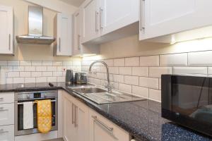 a kitchen with a sink and a microwave at Modern 2 Bed Attic Apartment in Brixton in London