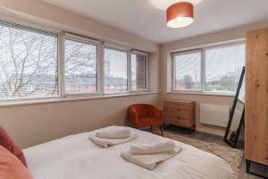 a bedroom with a bed and a chair and windows at Fantastic 1 Bed Flat Manchester - Sleeps 3 in Manchester