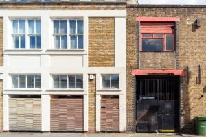 a brick building with two garage doors and a red window at Characterful 2 Bedroom Apartment in Brixton in London