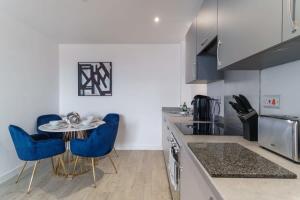 uma cozinha com uma mesa e algumas cadeiras azuis em Stunning 2 Bed Apartment in Salford with Views em Manchester