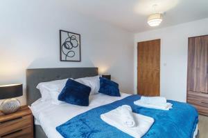 Un dormitorio con una cama azul y blanca con toallas. en Stunning 2 Bed Apartment in Salford with Views, en Mánchester