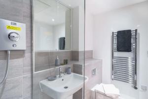 een witte badkamer met een wastafel en een spiegel bij Modern Manchester Studio Near Old Trafford in Manchester