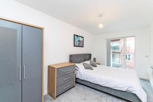 um quarto com uma cama, uma cómoda e uma janela em Contemporary 2 Bed Apartment in Central Manchester em Manchester