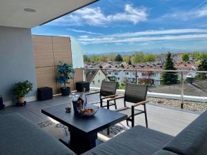ein Wohnzimmer mit einem Sofa und einem Tisch auf dem Balkon in der Unterkunft Penthouse Apartment mit Alpenblick in Friedrichshafen